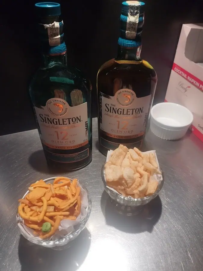 Crown KTV: Two bottles of Singleton 12 whisky with bowls of crackers and murukku-style snacks on a counter